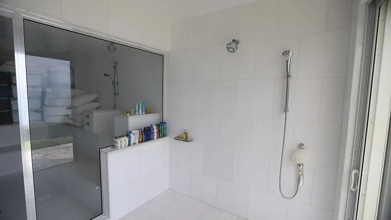 Dusche mit fester Glaswand in einem weiss gefliesten Bad